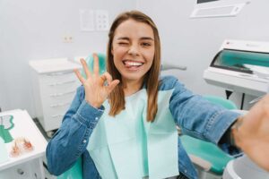 A dental hygienist using special instruments to clean a patient’s teeth while the patient reclines in a dental chair.